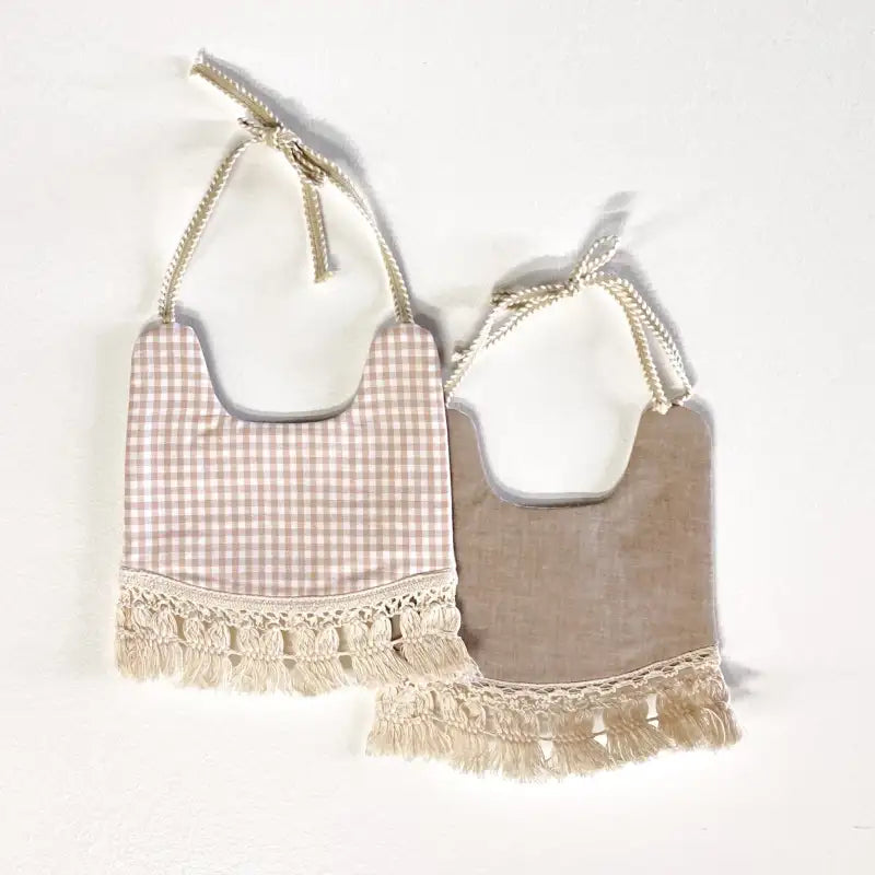 Two baby bibs with checkered and solid designs on a white background