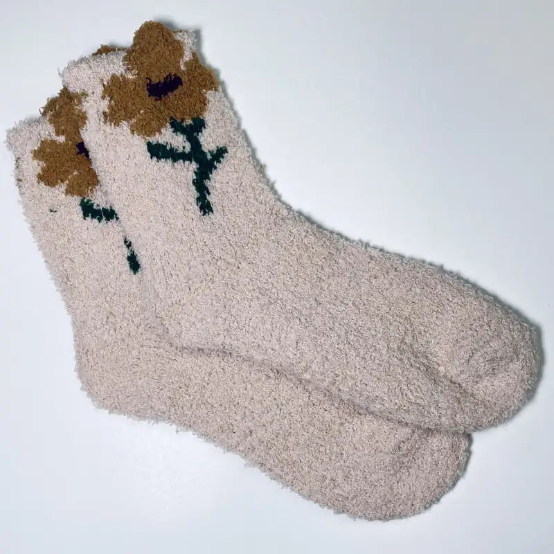 Beige fuzzy socks with brown flower designs on a white background