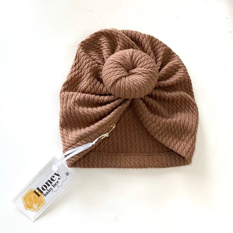 Brown knitted turban with a tag on a white background