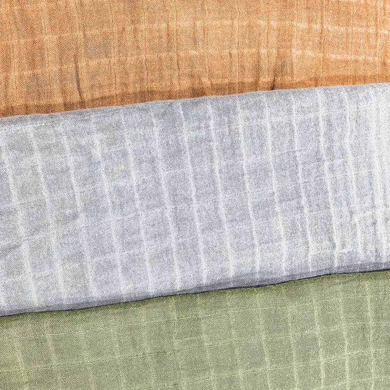 Close-up of fabric swatches in gray, green, and brown on a wooden surface