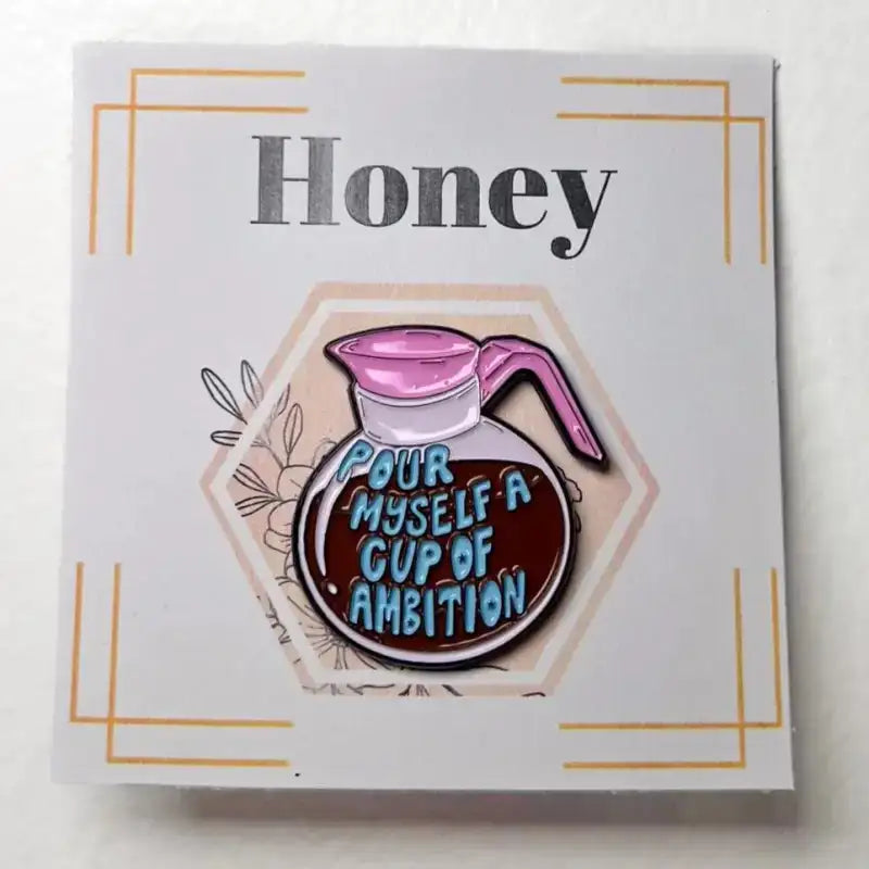 Enamel pin with coffee pot design and text on a white card with 'Honey' text.