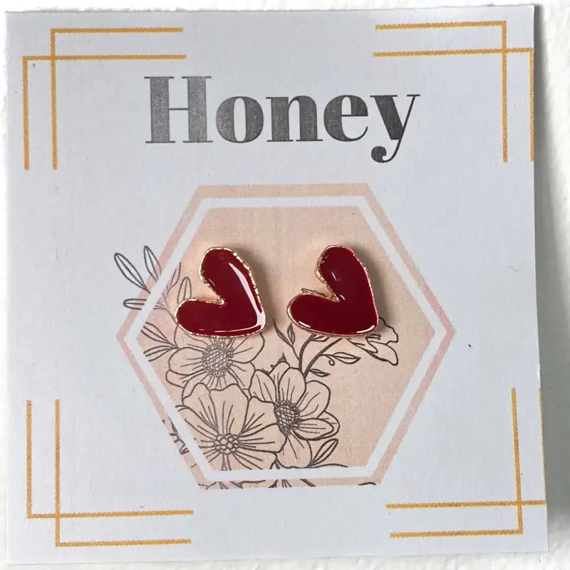 Red heart-shaped earrings on a card with floral design and 'Honey' text.
