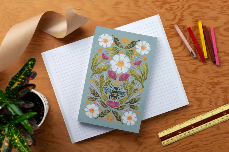 Decorative card with floral design on a wooden surface with stationery items.