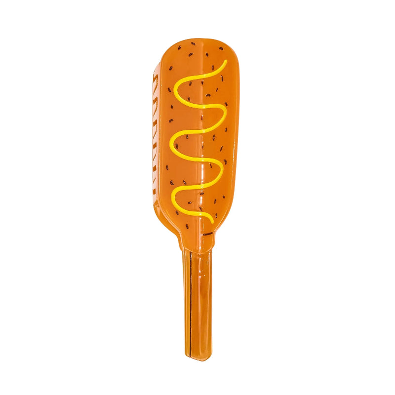 An inflatable hot dog toy with an orange body, black sesame seed details, and a yellow wavy line representing mustard, isolated on a white background.