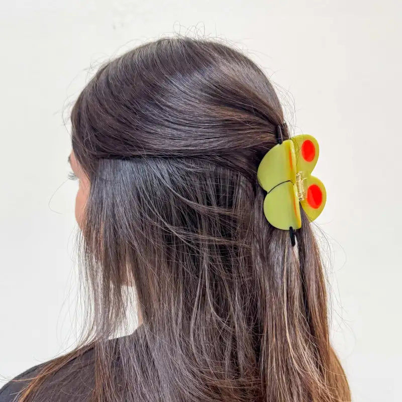 Olive hair clip on a person's hair against a white background