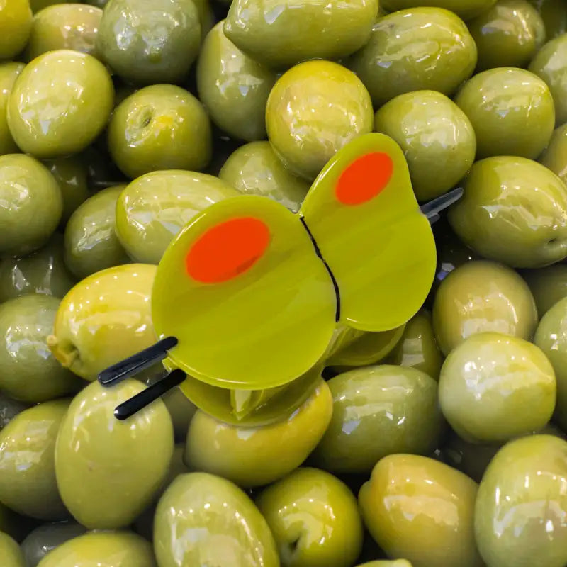 Large olive hair claw on a pile of green olives