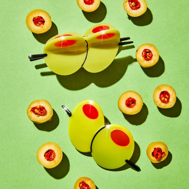 Olive hair claw with a pile of olives on a lime background
