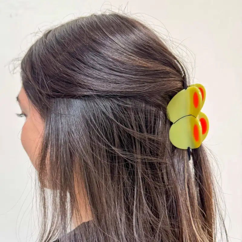 Person with a yellow olive hair claw in their hair against a white background