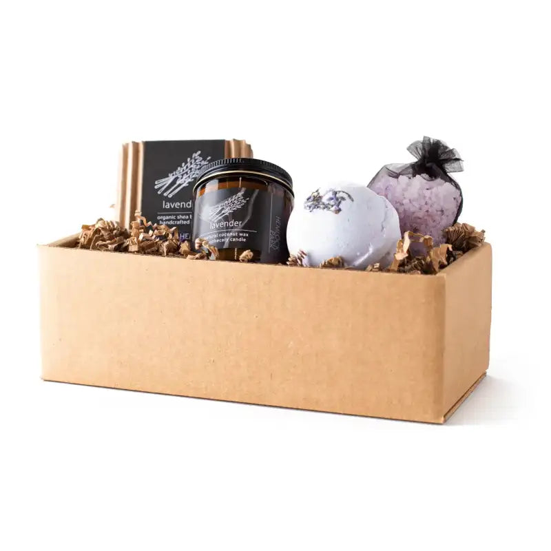 Gift box with lavender-themed products including a candle and bath bombs on a white background