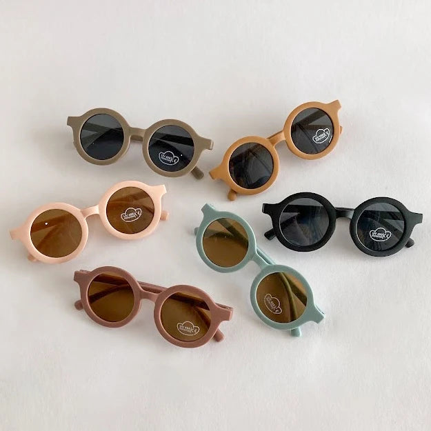 Set of colorful children's sunglasses on a light background