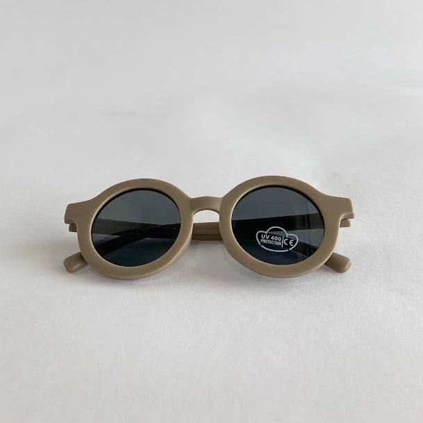 Round kids sunglasses with a beige frame on a light gray background