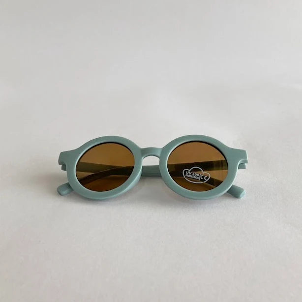 Round kids sunglasses with teal frame on a light gray background