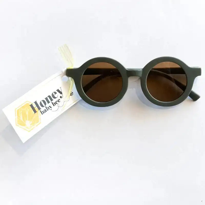 Round sunglasses with dark lenses on a white background, accompanied by a 'Honey' branded tag.