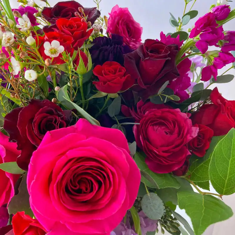 Bouquet of red and pink roses with green leaves on a light background
