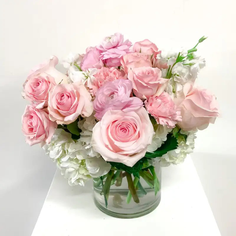 Bouquet of pink and white flowers in a clear vase on a white background