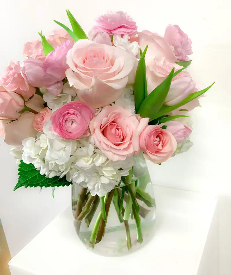 Bouquet of pink and white flowers in a clear vase on a white background