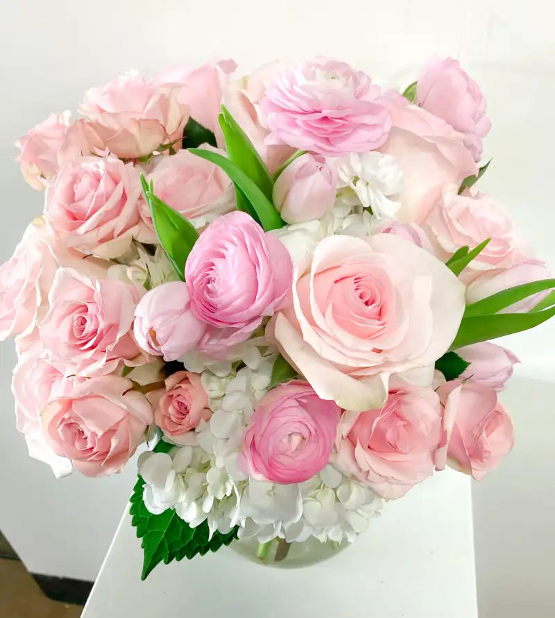 Bouquet of pink and white flowers with green leaves on a white background