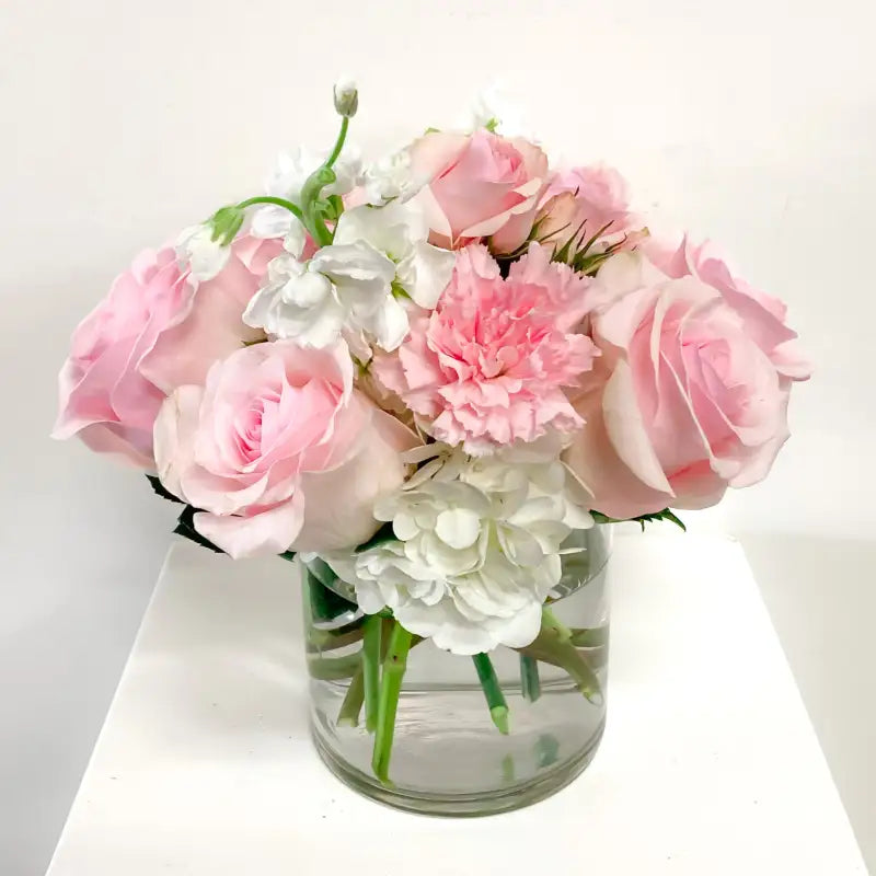 Bouquet of pink and white flowers in a clear vase on a white background