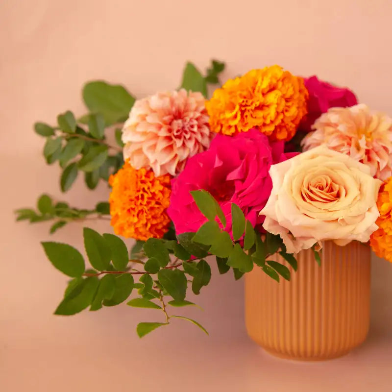 Bouquet of colorful flowers in a vase on a pink background