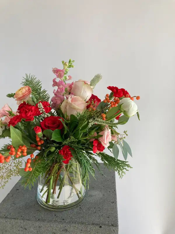 Bouquet of flowers in a clear vase on a concrete surface with a light gray background