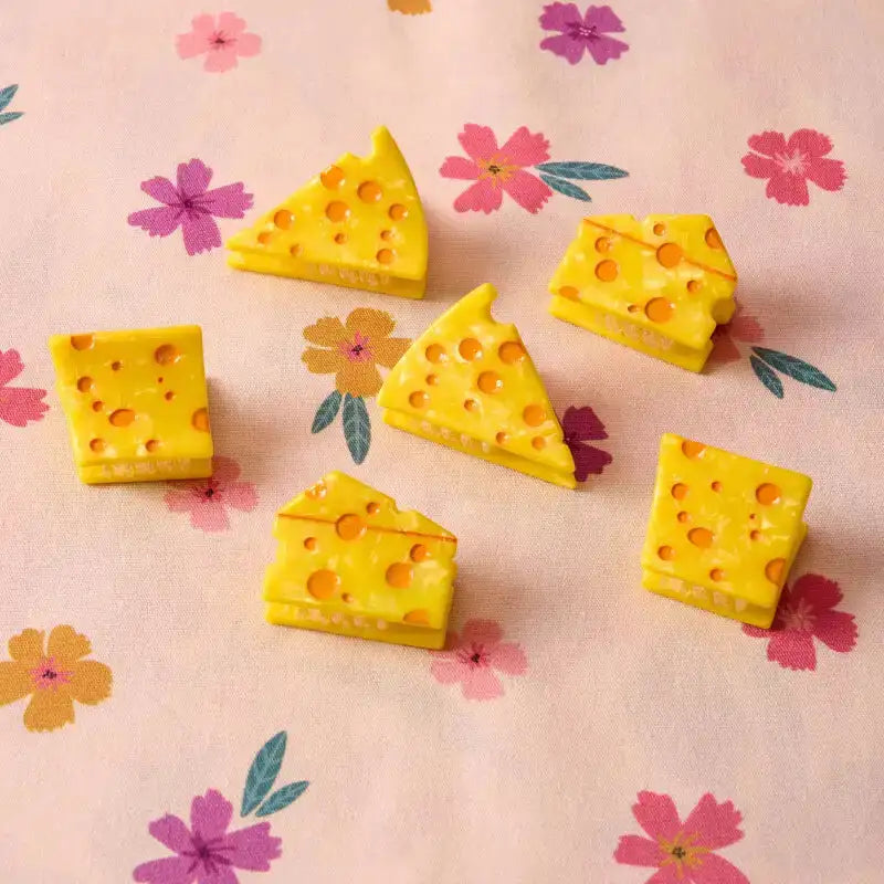 Yellow cheese-shaped erasers on a floral-patterned background