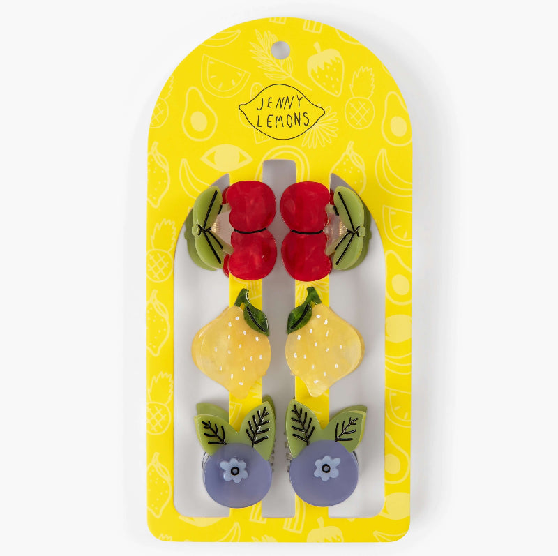 A set of six fruit-themed hair clips by Jenny Lemons, displayed on their original yellow backing card. The clips feature red cherries, yellow lemons, and purple blueberries with green leaves.