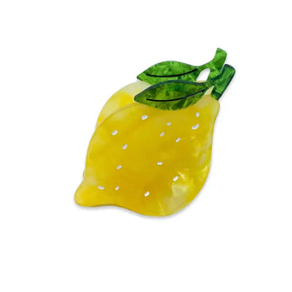 Yellow lemon-shaped hair claw with green leaves on a white background