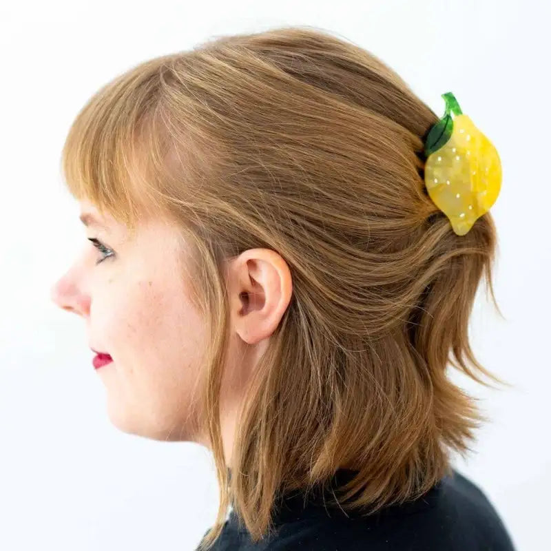 Person with a lemon-shaped hair claw in their hair on a white background