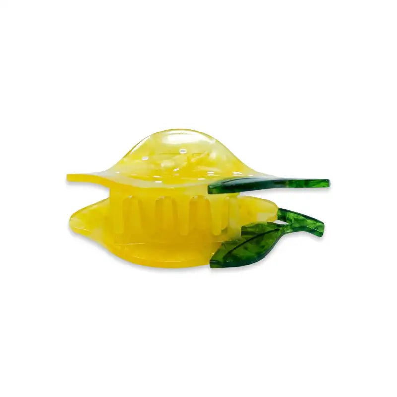 Yellow glass lemon with green leaves on a white background