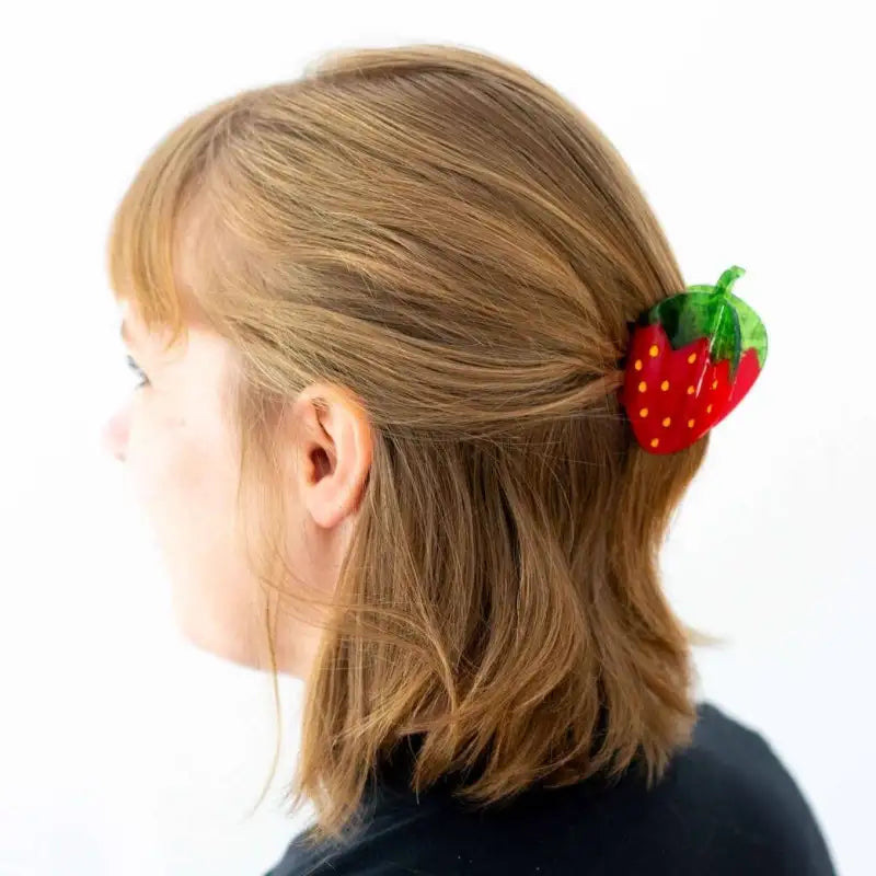 Person with strawberry-shaped hair claw in their hair on a white background
