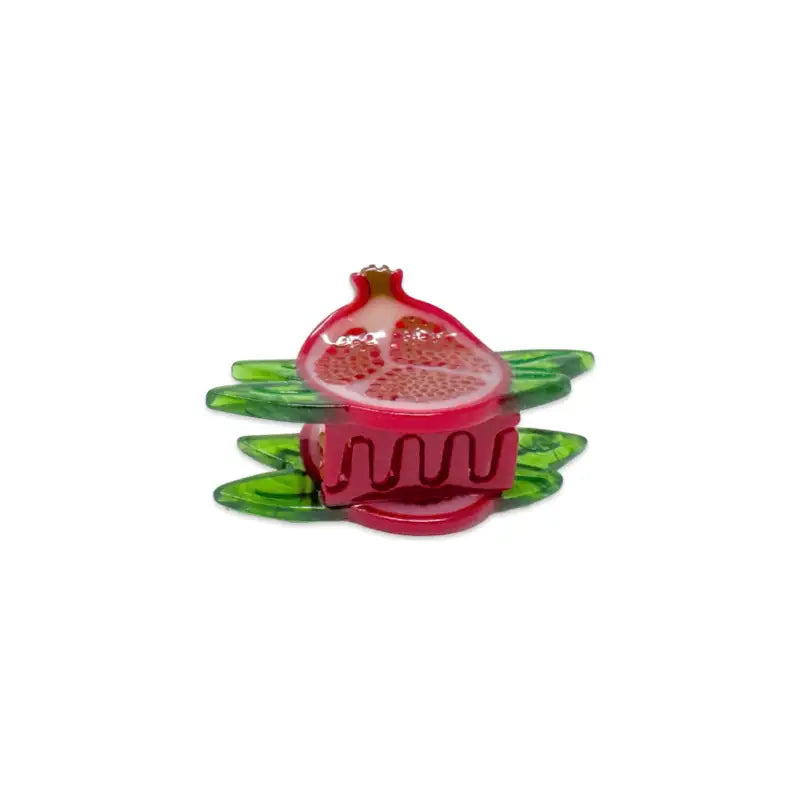 Decorative glass pomegranate with green leaves on a white background