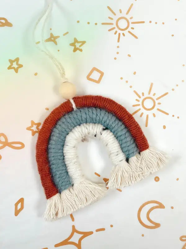 Handmade rainbow decoration with tassels on a light background with geometric patterns