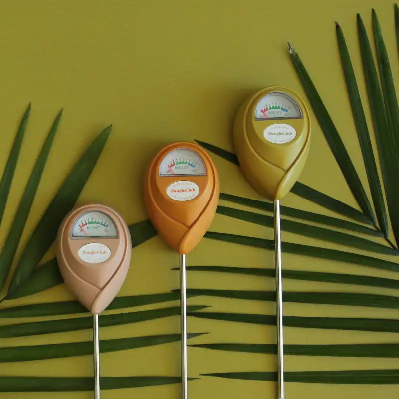 Three soil testers on a yellow background with green leaves