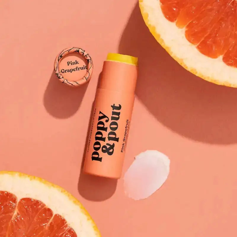 Lip balm with 'Poppy & Point' branding on a pink background with grapefruit slices.