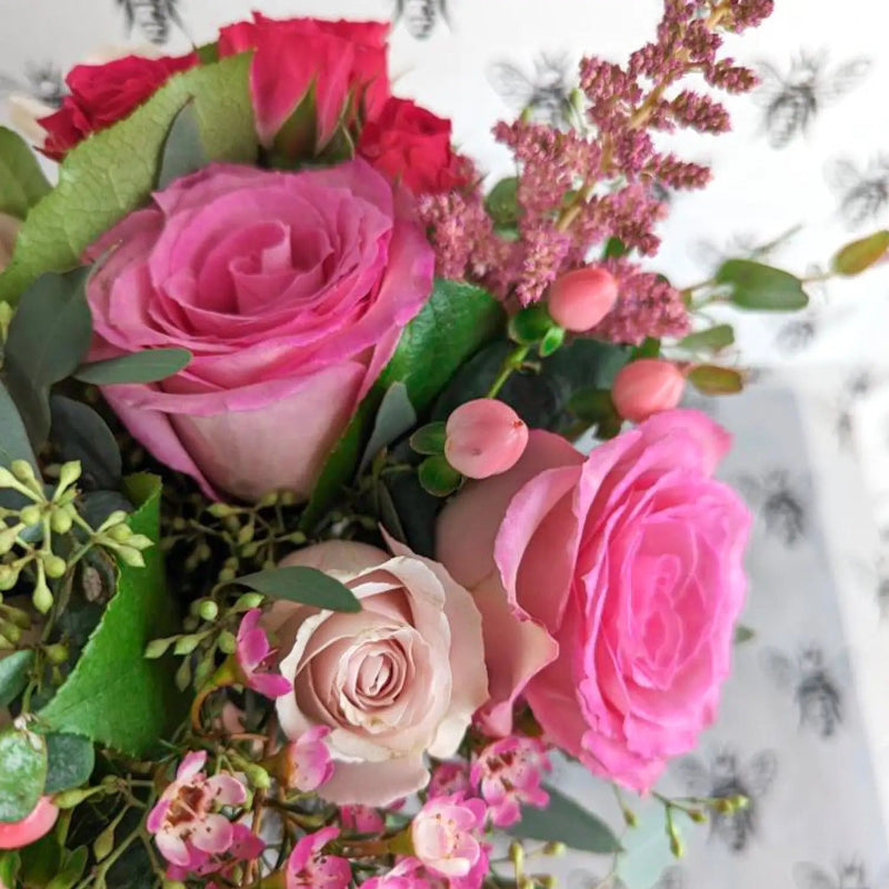 Bouquet of pink and red roses with greenery on a marble background