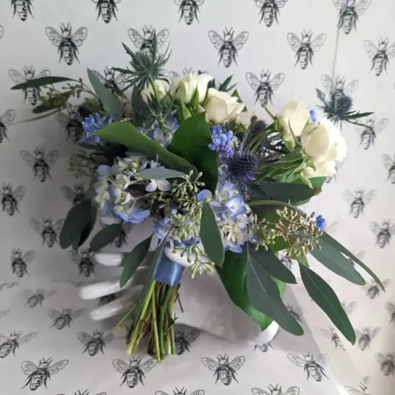 Overhead view of blue and white nosegay bouquet with eucalyptus leaves, white roses, and pale blue accents