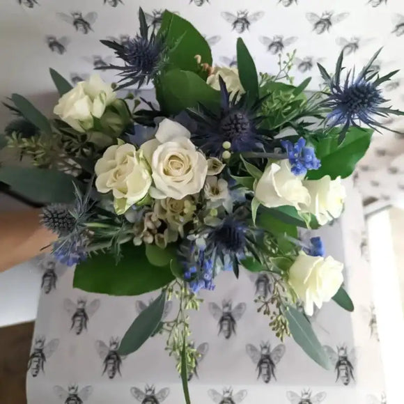 Blue and white nosegay bouquet with white roses, blue thistle, eucalyptus, and textured greenery