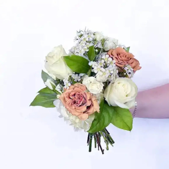 Neutral nosegay bouquet with peach roses, ivory blooms, delicate white filler flowers, and green leaves