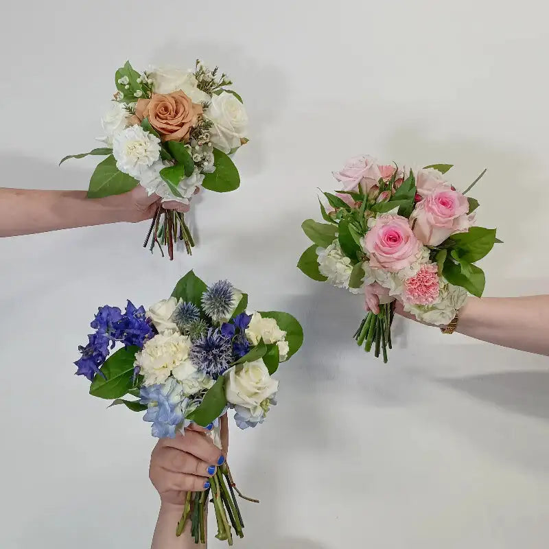 Hand tied nosegay bouquet with ivory roses, peach rose center, white filler flowers, and fresh greenery