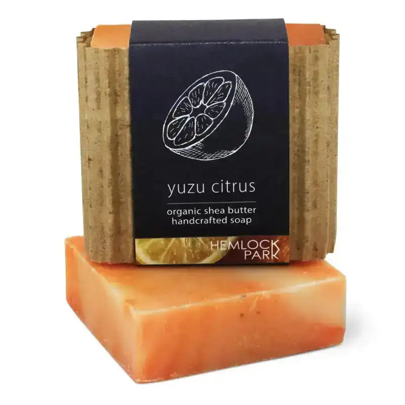 Two bars of soap, one stacked on top of the other, with a label indicating 'yuzu citrus' and 'organic shea butter'.