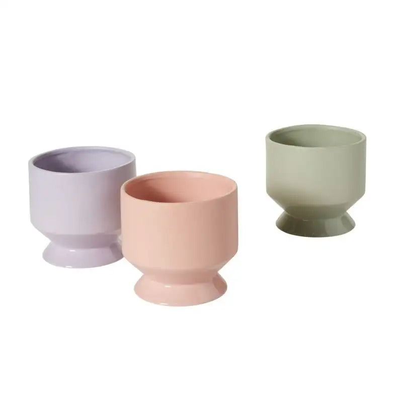 Three ceramic cups in pastel colors on a white background