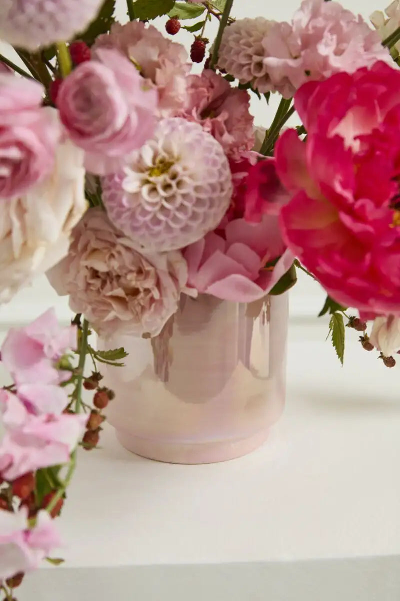 Pink and red flowers in a vase on a white surface