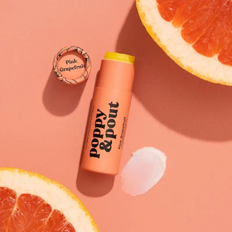 Lip balm with 'Poppy & Pout' branding on a pink background with grapefruit slices.