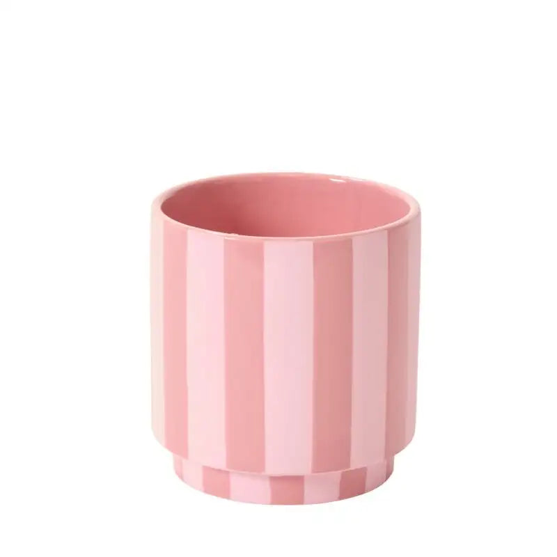 Pink ceramic cup with vertical stripes on a white background