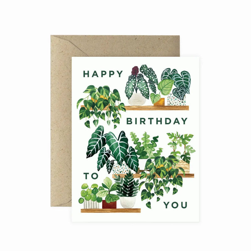 A birthday greeting card with a floral design, featuring magnolia flowers and leaves, and the text 'Happiest Birthday'. It comes with a brown envelope.