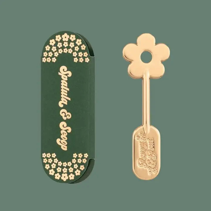 Gold flower-shaped spoon with green case on a transparent background