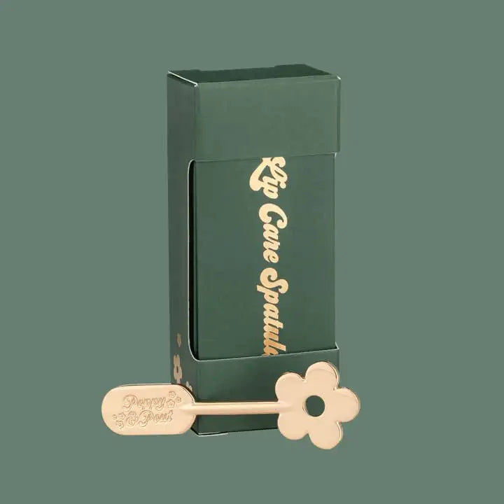 Lip care spatula with green packaging on a green background