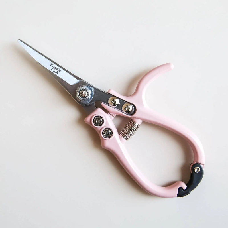 Pink-handled scissors with metal blades on a light beige background