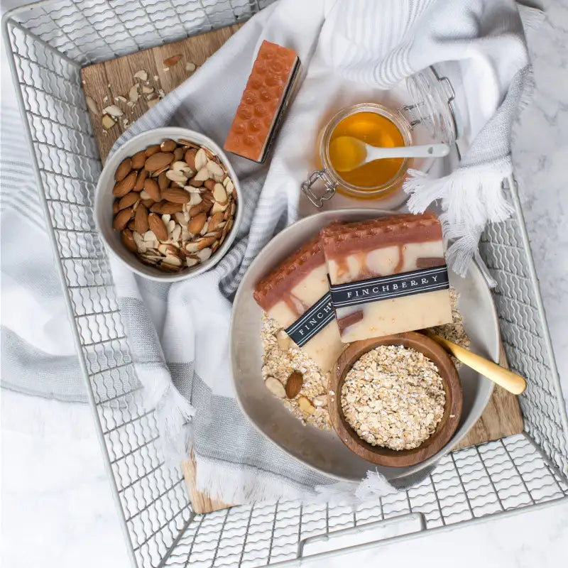 Bowl of almonds, jar of honey, and soap with 'Fincherry' branding on a metal tray.
