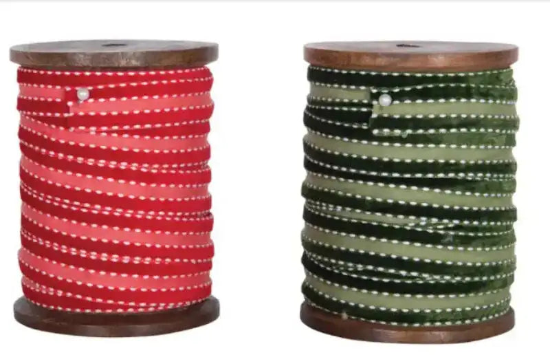 Two spools of red and green thread on wooden spools against a white background